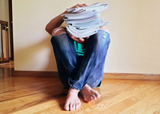 Man sitting on floor with a stack of papers 